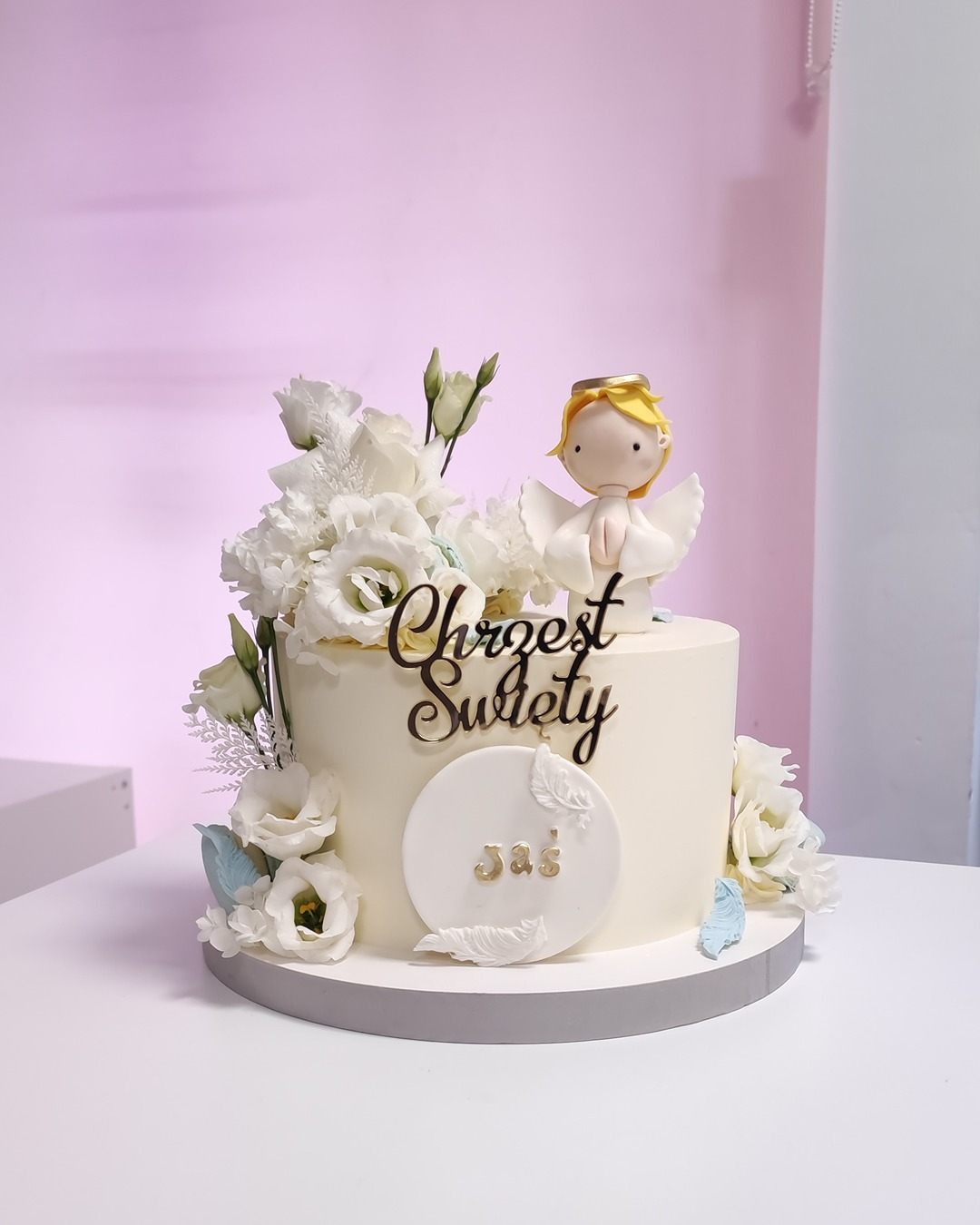 Biały tort na chrzest z dodatkami kwiatów i aniołkiem - Pracownia Kremlove Biały Tort na chrzciny z dodatkami kwiatów